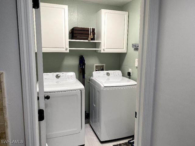 washroom featuring cabinets and washer and clothes dryer