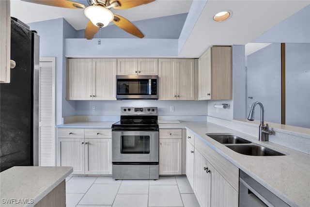 kitchen with lofted ceiling, appliances with stainless steel finishes, sink, and light tile patterned floors