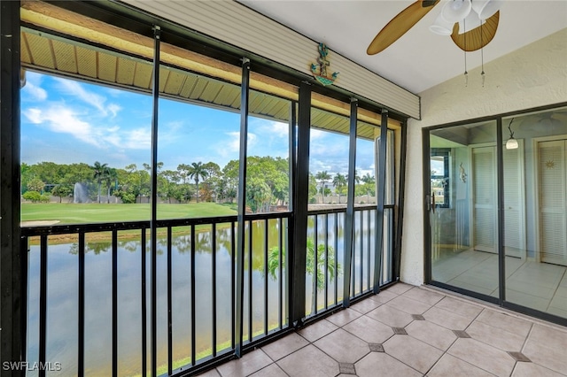 unfurnished sunroom featuring ceiling fan and a water view