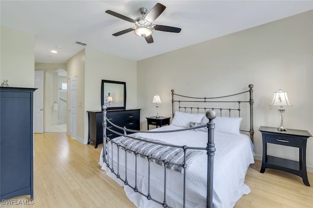 bedroom featuring light wood-type flooring, arched walkways, visible vents, and baseboards