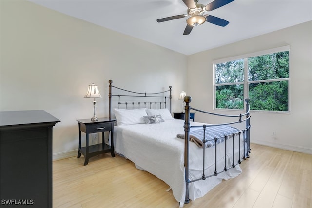 bedroom with ceiling fan, light wood finished floors, and baseboards