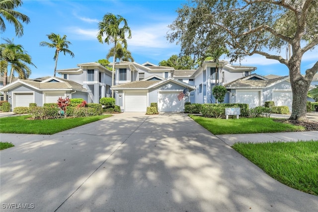 view of front of house with an attached garage, concrete driveway, a residential view, stucco siding, and a front lawn