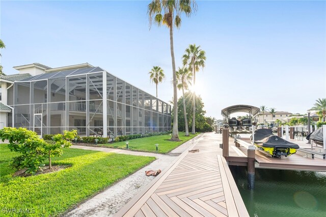 view of dock with glass enclosure, a yard, and a water view