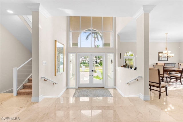 entryway featuring ornamental molding, a towering ceiling, french doors, light tile patterned floors, and a notable chandelier