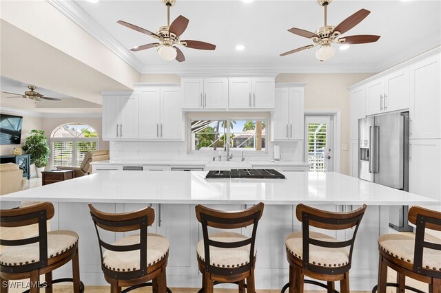 kitchen with backsplash, crown molding, a spacious island, and white cabinets