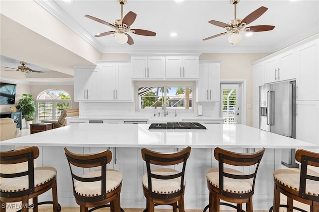 kitchen featuring a large island, high end fridge, light countertops, ornamental molding, and white cabinets