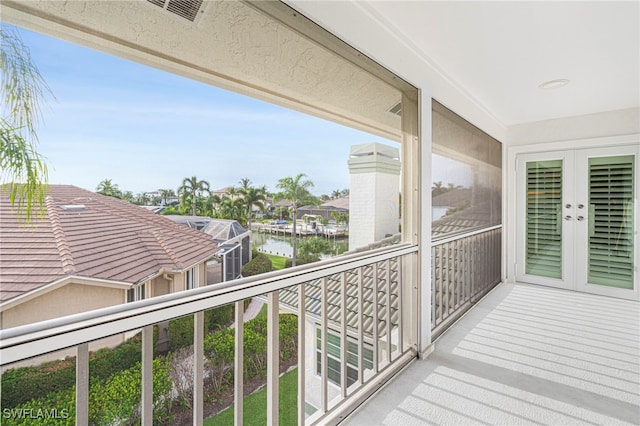 balcony with french doors, a water view, and visible vents