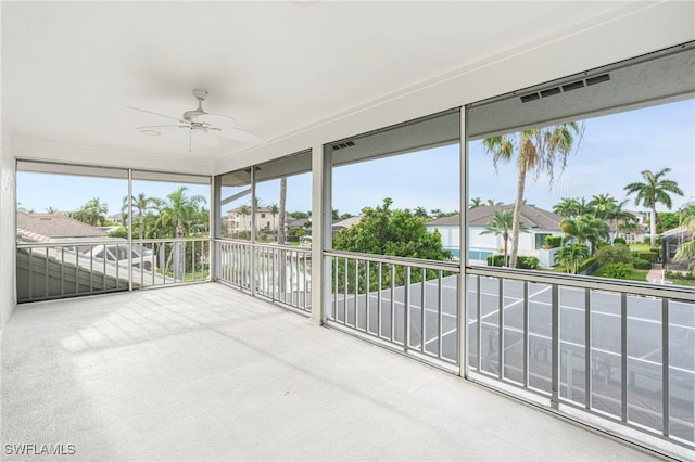 unfurnished sunroom with a residential view and a ceiling fan