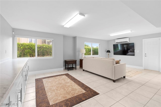 living area with an AC wall unit, light tile patterned flooring, and baseboards