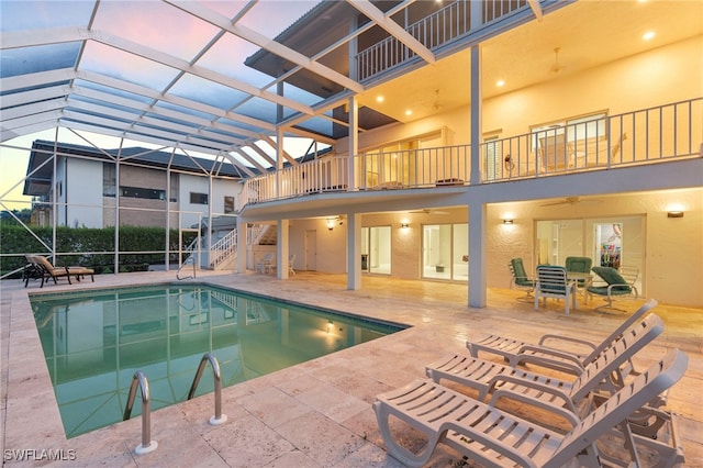 pool with glass enclosure, stairway, a patio area, and a ceiling fan