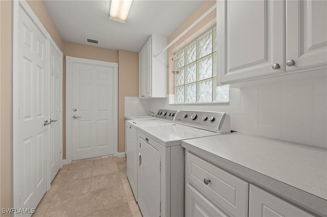 laundry area featuring cabinet space, light tile patterned floors, visible vents, and washing machine and clothes dryer