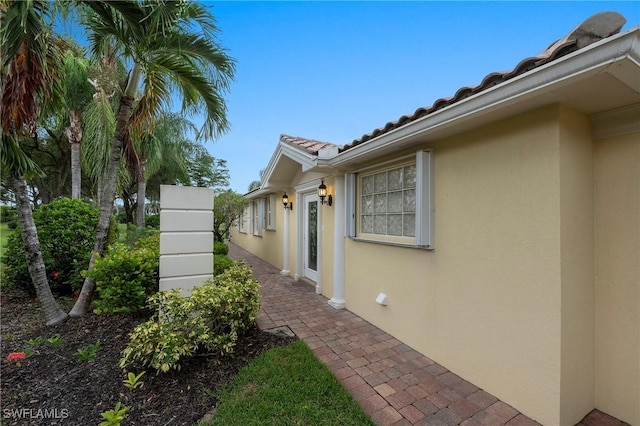 view of side of property featuring a patio area, a tile roof, and stucco siding