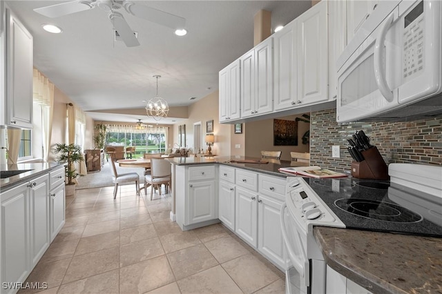 kitchen with white cabinets, white microwave, a peninsula, backsplash, and range with electric stovetop