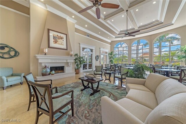 living area with coffered ceiling, a towering ceiling, ceiling fan, ornamental molding, and a high end fireplace