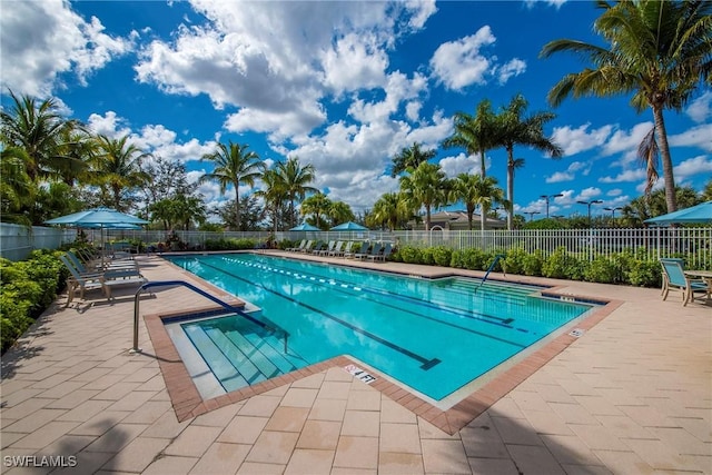 pool with a patio area and fence