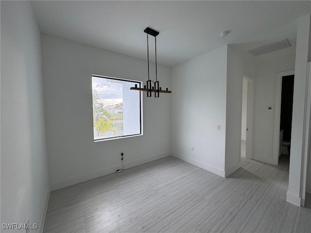 unfurnished dining area featuring light hardwood / wood-style floors and a chandelier