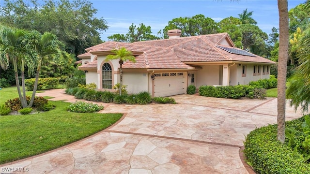 view of front facade with a chimney, concrete driveway, a garage, a tiled roof, and a front lawn