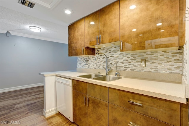 kitchen featuring tasteful backsplash, sink, light wood-type flooring, a textured ceiling, and white dishwasher