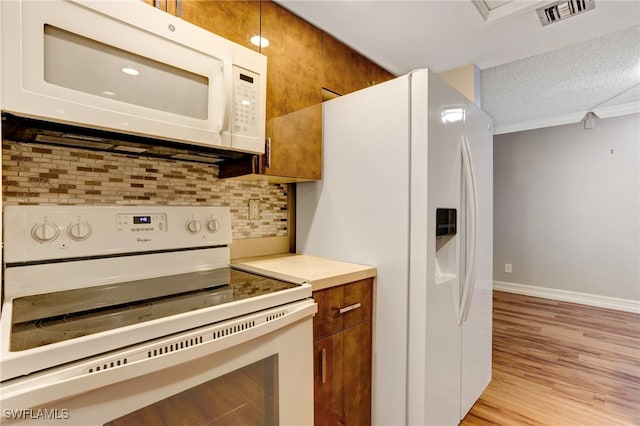 kitchen featuring a textured ceiling, white appliances, backsplash, and light hardwood / wood-style flooring