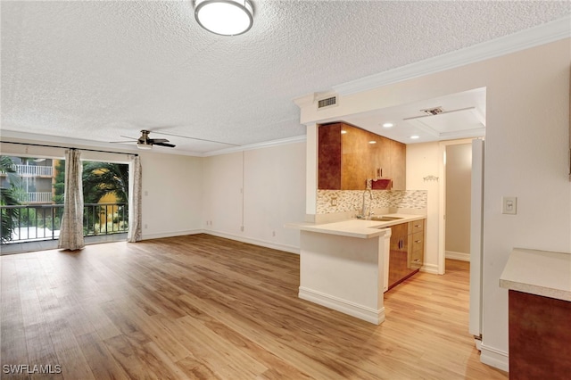 kitchen with ceiling fan, light wood-type flooring, decorative backsplash, sink, and kitchen peninsula