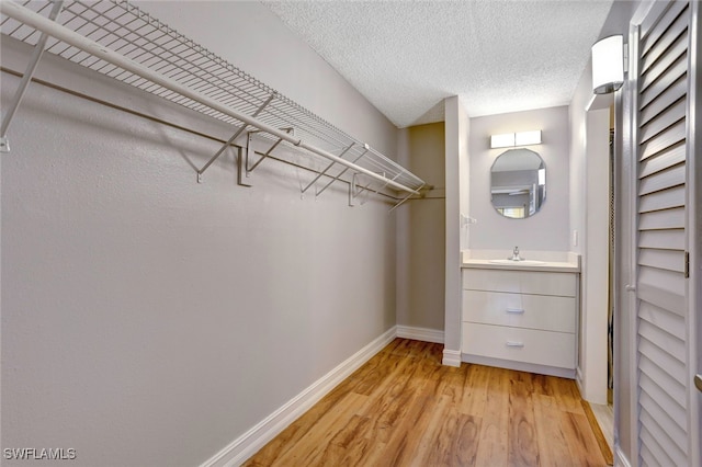 walk in closet with light hardwood / wood-style floors and sink