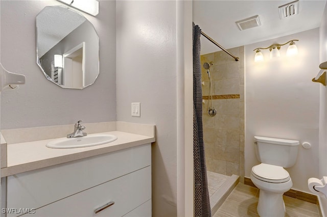 bathroom featuring vanity, a tile shower, and toilet