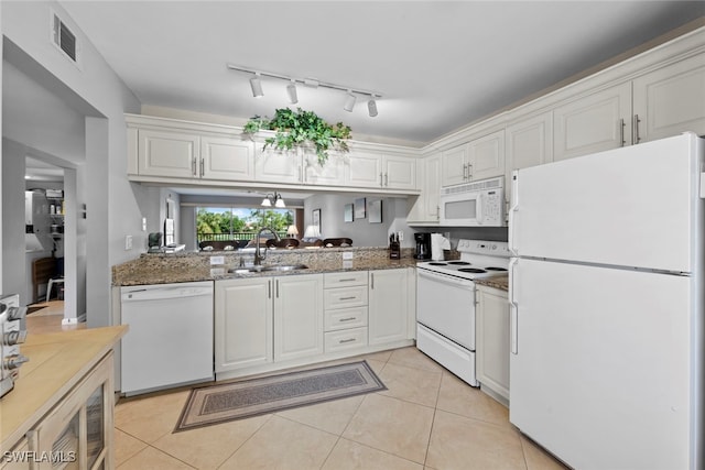 kitchen featuring dark stone counters, white cabinetry, sink, rail lighting, and white appliances