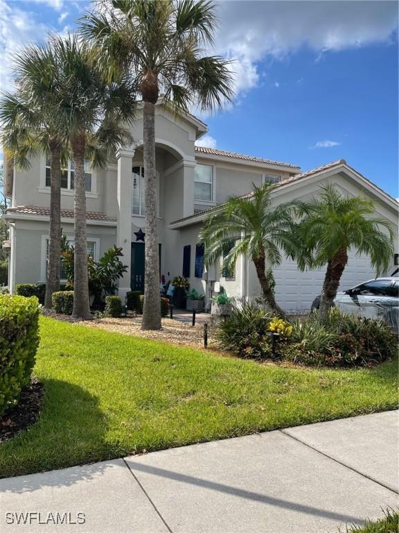 view of front of house with an attached garage, stucco siding, a tile roof, and a front yard