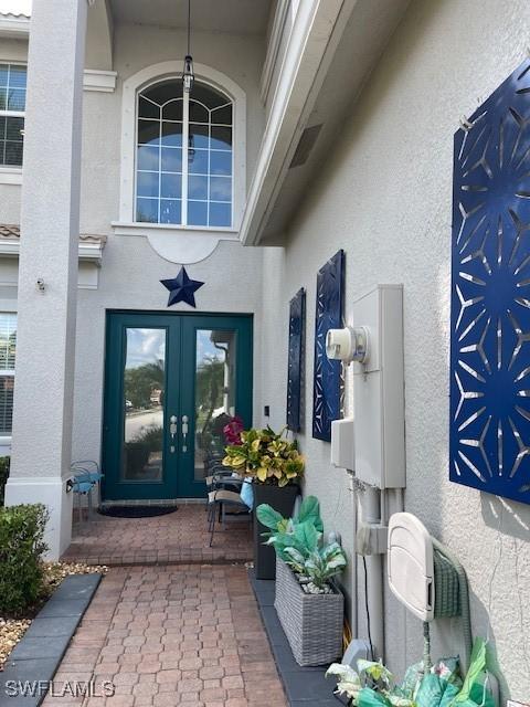 view of exterior entry featuring french doors and stucco siding