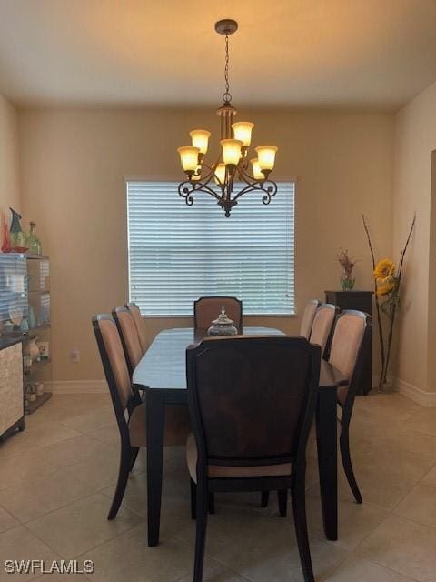 dining space with a chandelier, baseboards, and light tile patterned floors