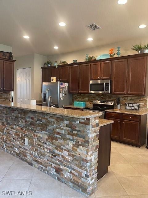 kitchen featuring stainless steel appliances, backsplash, and light stone counters