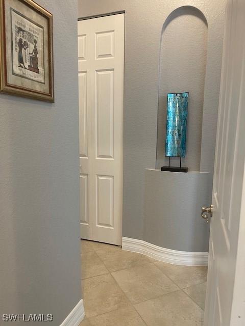 hallway with light tile patterned flooring and baseboards