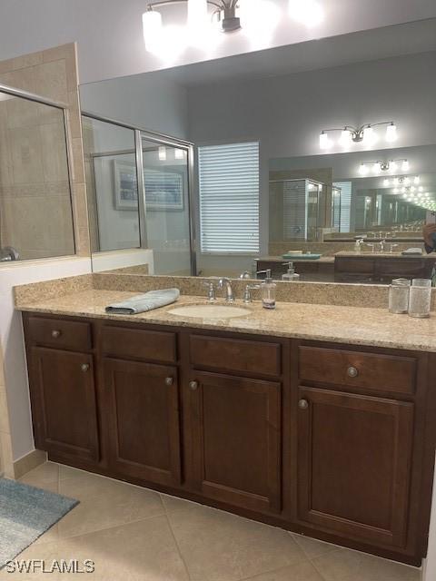 bathroom with tile patterned floors, a shower with door, and vanity