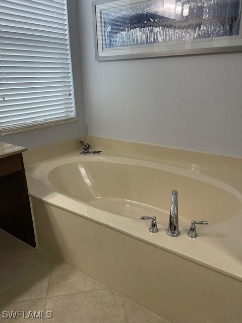 full bath with tile patterned flooring, a bath, and vanity