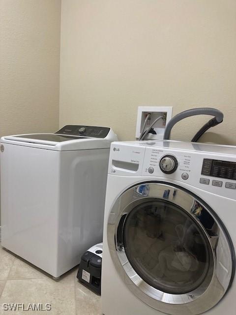 clothes washing area with laundry area, separate washer and dryer, and light tile patterned flooring