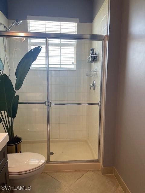 bathroom with baseboards, toilet, tile patterned floors, vanity, and a shower stall