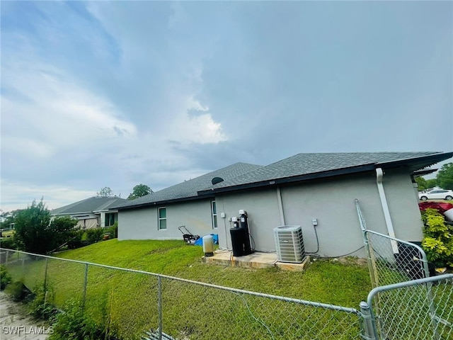 rear view of house with cooling unit and a lawn