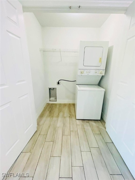 clothes washing area featuring stacked washer / dryer and light hardwood / wood-style flooring