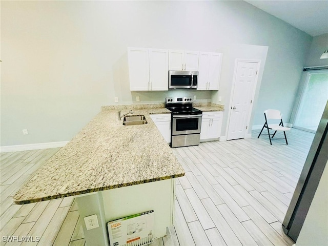 kitchen with kitchen peninsula, vaulted ceiling, light stone counters, and stainless steel appliances