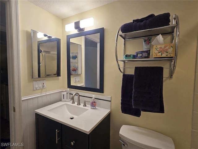 bathroom featuring a textured ceiling, vanity, and toilet