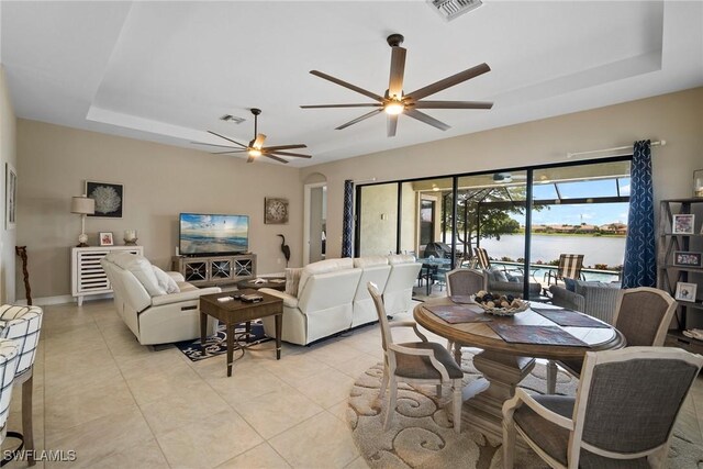 tiled dining area featuring a raised ceiling and ceiling fan