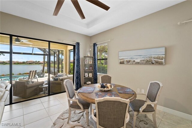 dining room featuring ceiling fan, light tile patterned floors, and a water view