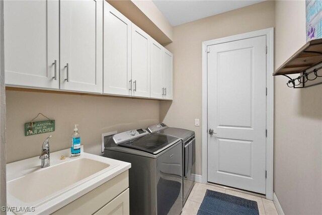 washroom with light tile patterned floors, cabinets, sink, and independent washer and dryer