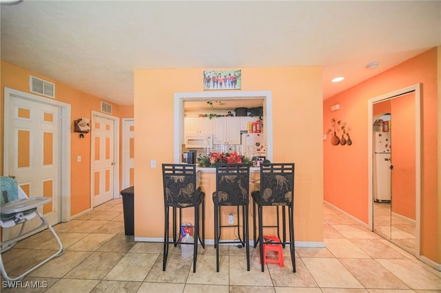 bar with white cabinets, white appliances, and light tile patterned floors