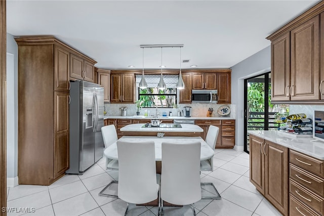 kitchen featuring a wealth of natural light, hanging light fixtures, appliances with stainless steel finishes, and light tile patterned flooring