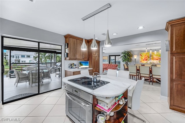 kitchen featuring electric cooktop, hanging light fixtures, a wealth of natural light, and oven