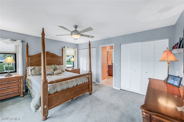 carpeted bedroom featuring two closets, ceiling fan, and ensuite bathroom