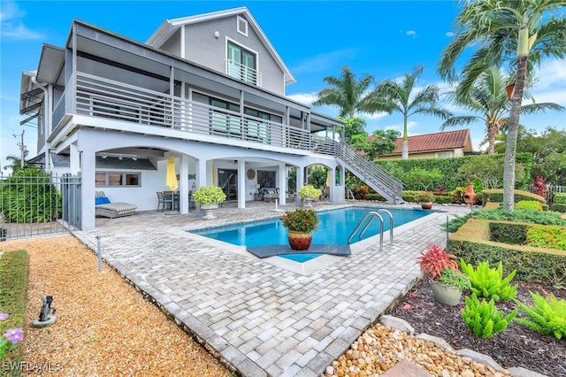 back of property featuring a fenced in pool, a patio, and a balcony