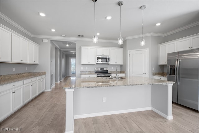 kitchen featuring decorative light fixtures, light stone counters, stainless steel appliances, white cabinetry, and a center island with sink