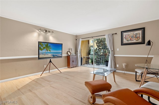 living room with baseboards, crown molding, and wood finished floors